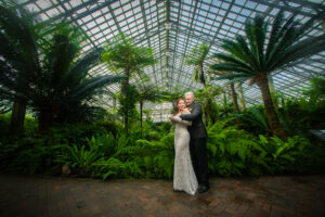 Groom hugging the bride in front of a tropical garden at the Garfield Park Conservatory in Chicago