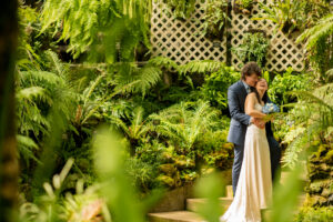 Groom with the bride smiling in a tropical exhibit at the Lincoln Park Conservatory in Chicago